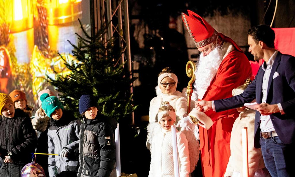 Foto: Moderator Felix Groß, 2 als Engelchen verkleidete Kinder, weitere nicht verkleidete Kinder begrüßen Jonny Reinhardt als Nikolaus.